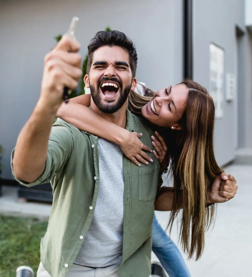 Happy new homeowners holding up the keys to their home
